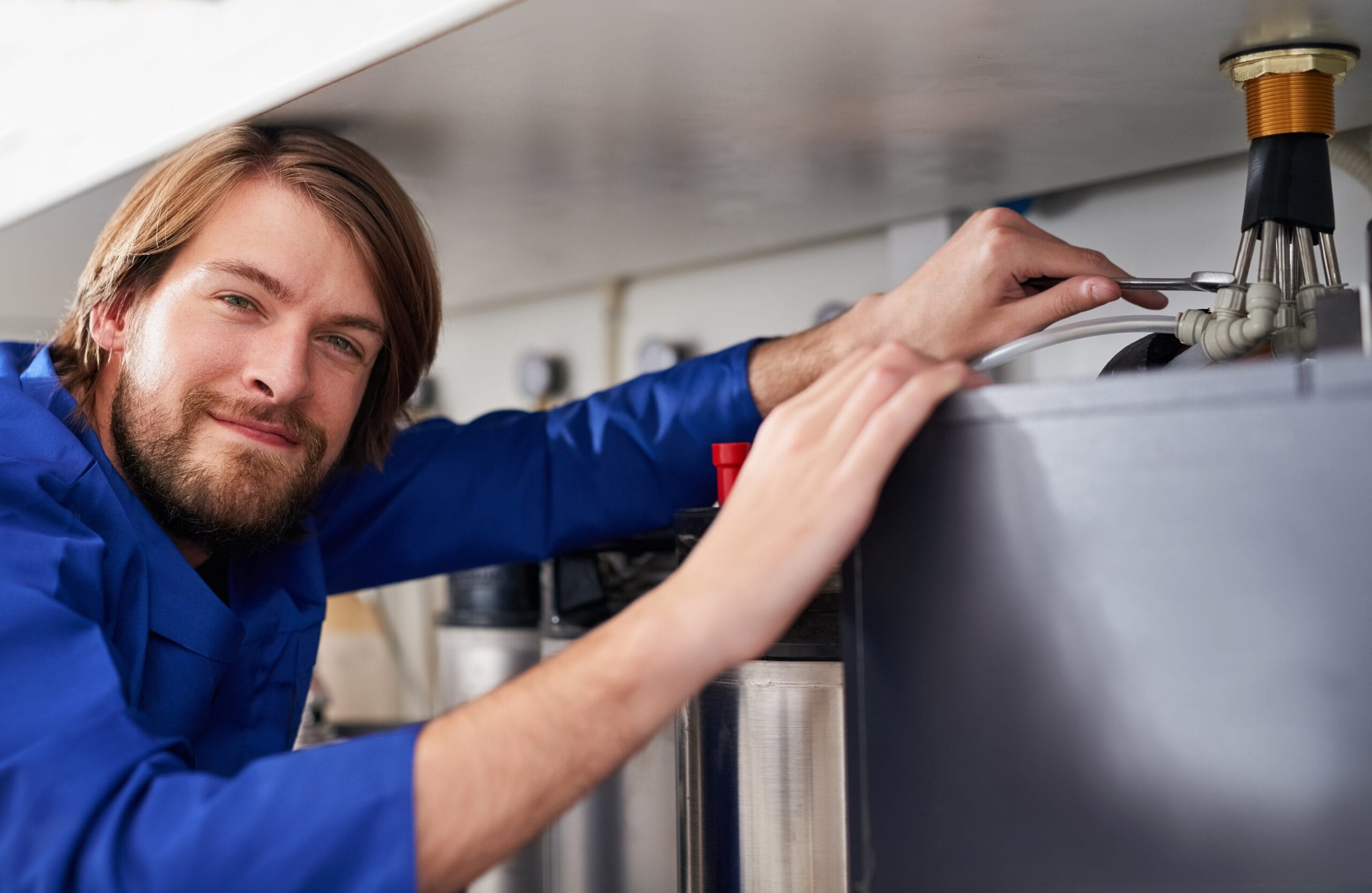 Technician servicing a residential water heater tank in Campbell